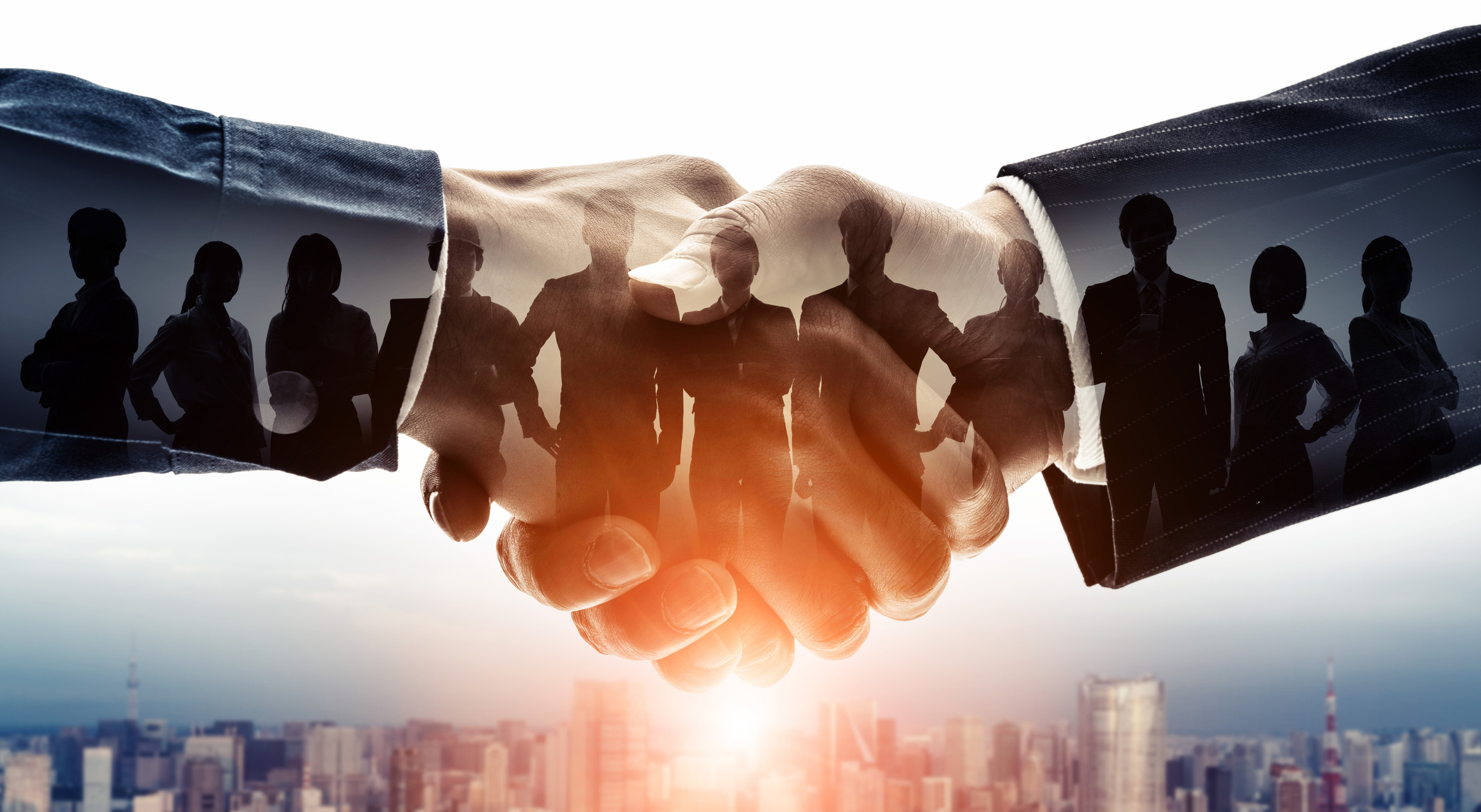 Modern image of shaking hands with silhouettes of business people displaying partnership.