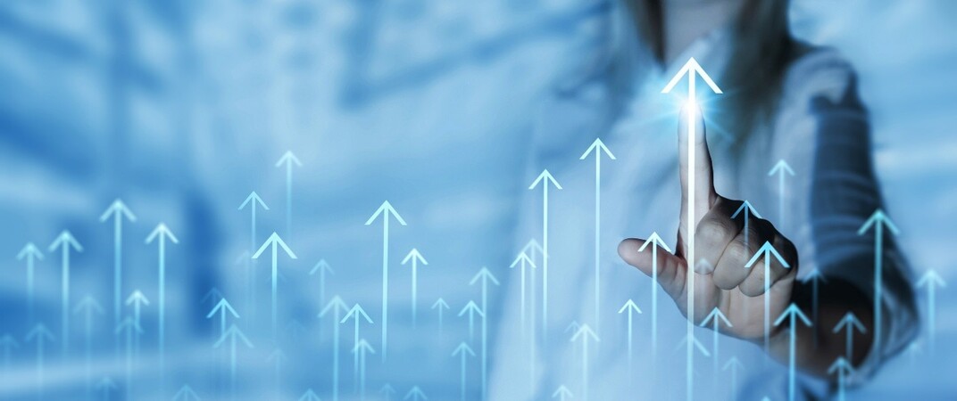Businessperson pointing at a rising arrow on a digital screen, symbolising growth and success.