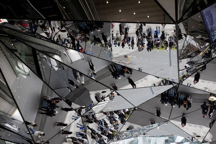 Abstract-looking image of people reflected in a mirrored ceiling. 